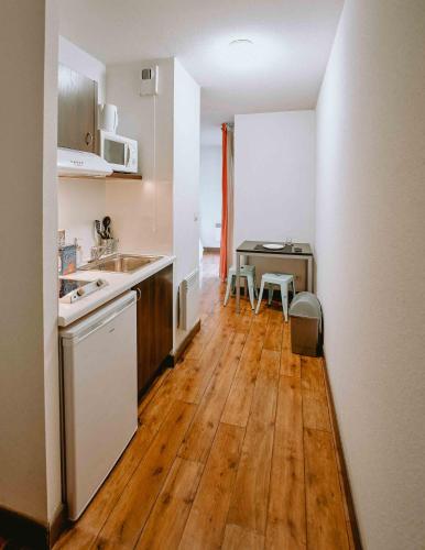 a kitchen with a sink and a wooden floor at Zenao Appart Hôtel Nevers Quai de Loire in Nevers