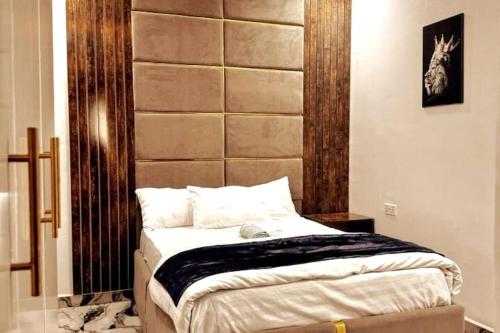a bedroom with a bed with a wooden headboard at Luxurious Home - The Paletinos in Umuahia