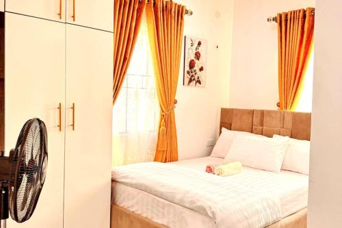 a bedroom with a bed with an orange curtain at Luxurious Home - The Paletinos in Umuahia