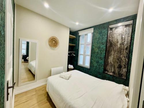 a bedroom with a white bed and a green wall at Le Besson, 2 pièces au cœur de la ville in Trouville-sur-Mer