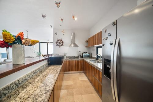 a kitchen with a stainless steel refrigerator and wooden cabinets at 4 Bedroom Siela Beachfront Luxury Apartment in San Bruno