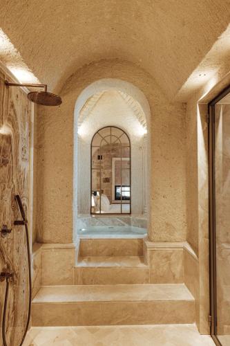 a room with a bath tub with a mirror at Via Regia Cappadocia Hotel in Uchisar