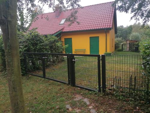 a yellow and green house behind a fence at Haus 9 am Fluss in Witnica