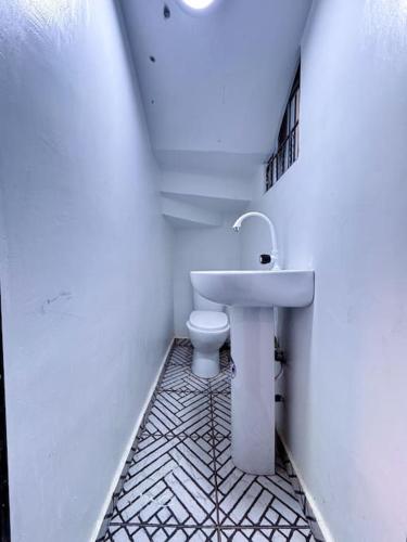 a white bathroom with a toilet and a sink at Cozy & Serene Sanctuary -The Paletinos Homes in Umuahia