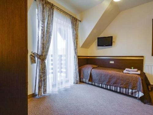 a bedroom with a bed and a large window at Hotel Orlik in Krynica Zdrój