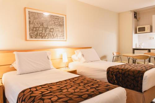 a hotel room with two beds and a table at Punta Trouville Hotel in Montevideo