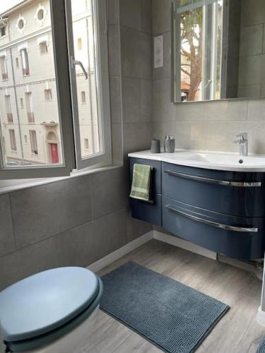 une salle de bain avec toilettes, lavabo et fenêtre dans l'établissement tres bel appartement au calme entre gare et centre, à Perpignan