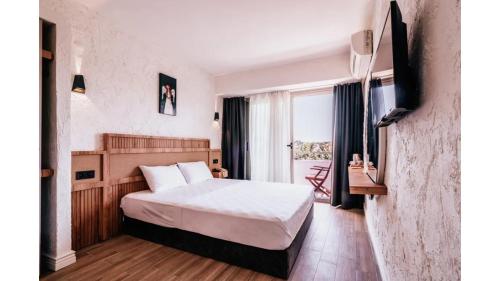 a hotel room with a bed and a television at Sirius Mİ Sun Paradise Hotel Çeşme in Çeşme