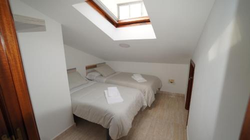 Una pequeña habitación con dos camas y una ventana. en A Xanota, en Combarro