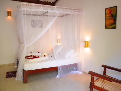 a bedroom with a bed with a mosquito net at Pitaramba Lodge in Bentota