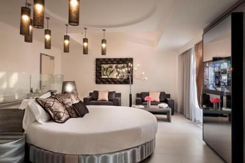 a bedroom with a large bed and a living room at Grand Hotel Resort&SPA Ma&Ma - Adults Only in La Maddalena