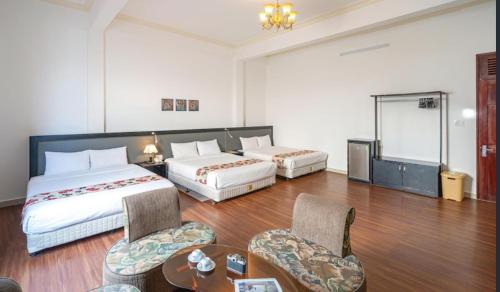 a hotel room with two beds and a table and chairs at LILLY Hotel in Da Lat