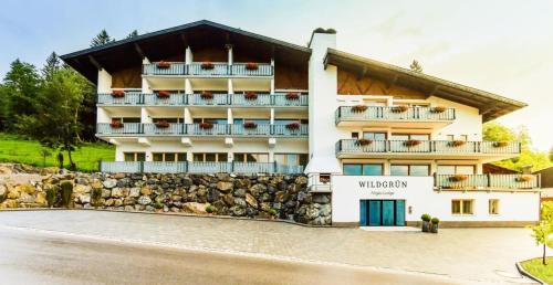 a hotel building with a stone wall at Wildgrün Maxi Lodge 7 in Pfronten