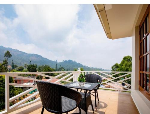 a table and chairs on a balcony with a view at Habba Kadal Kashmiri Heritage Hotel & Hub in Coonoor