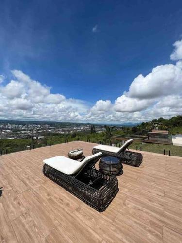 a patio with chairs and tables on a wooden deck at Luxury Villa Spectacular Views Sauna Jacuzzi BBQ in Dosquebradas