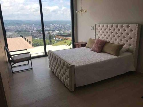 a bedroom with a large bed and a large window at Luxury Villa Spectacular Views Sauna Jacuzzi BBQ in Dosquebradas