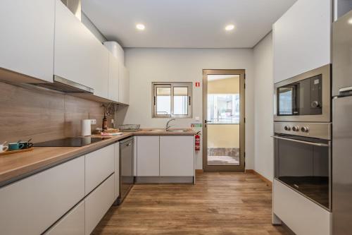 a kitchen with white cabinets and wooden floors at Casa das Raposinhas I in Funchal