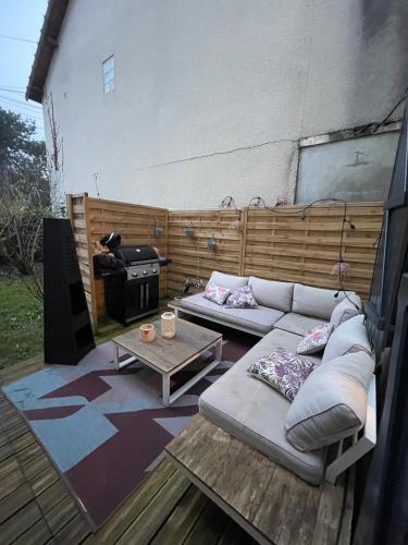 une terrasse avec un canapé, une table et une cuisinière dans l'établissement Maison Jardin des Plantes Le Mans, au Mans