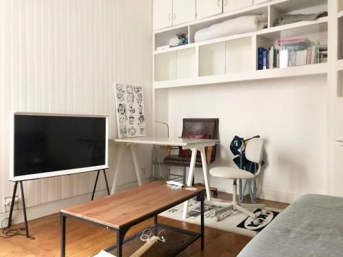 un salon avec une télévision et une table dans l'établissement Joli studio Boulogne proche Paris, à Boulogne-Billancourt
