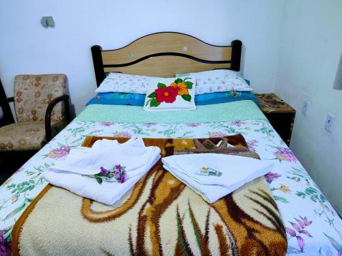 a bed with white towels and flowers on it at Minha casa pousada in Botucatu