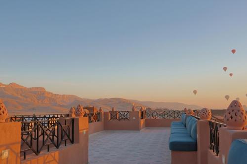a balcony with couches and hot air balloons in the sky at Malkata House - Boutique hotel and restaurant in Luxor