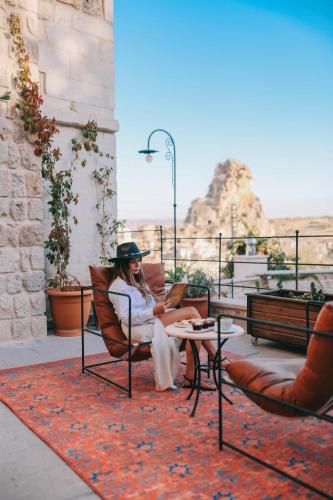 a woman sitting in a chair on a patio at Cappadocia Vita Cave Hotel in Urgup