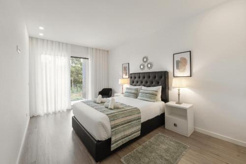 a white bedroom with a large bed and a window at Coastal Sea Jewel in Nazaré