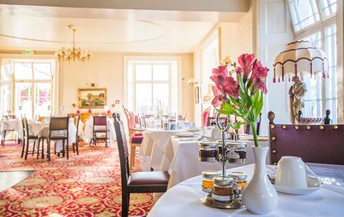un restaurante con mesas y sillas con flores. en Haddon House Hotel en Bridport
