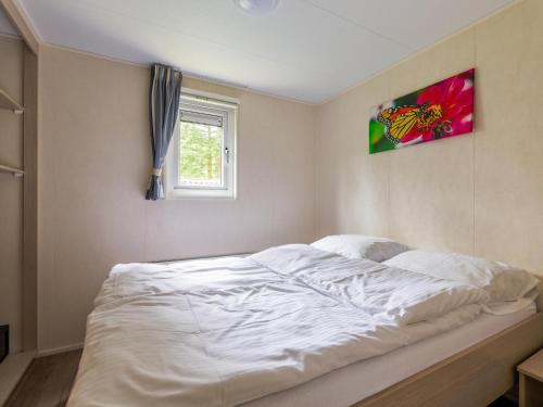 a large white bed in a bedroom with a window at Easy Chalet in Vessem
