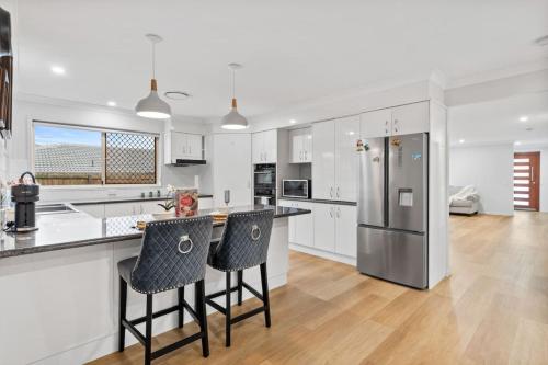 a kitchen with white cabinets and a stainless steel refrigerator at Stunning 5BR Big Modern Home with Parking Malls and Parks in Brisbane