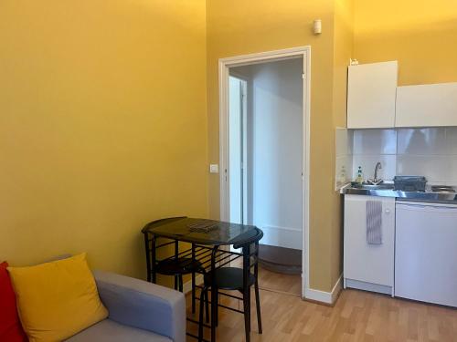 a living room with a table and a kitchen at Le coup de cœur Parisien in Yerres