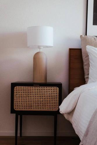 a lamp sitting on a table next to a bed at Hidden Retreats The Blausee in Frutigen