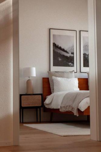 a bedroom with a bed with two pictures on the wall at Hidden Retreats The Blausee in Frutigen