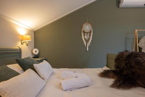 a bed with white pillows and a clock on the wall at B&B Iets Zeeuws in Kats