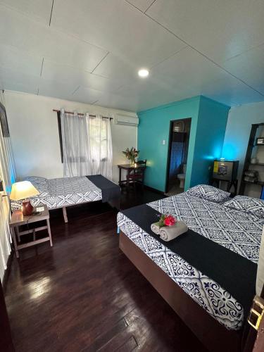 two beds in a room with blue walls and wooden floors at Hotel Maritza in Puerto Viejo