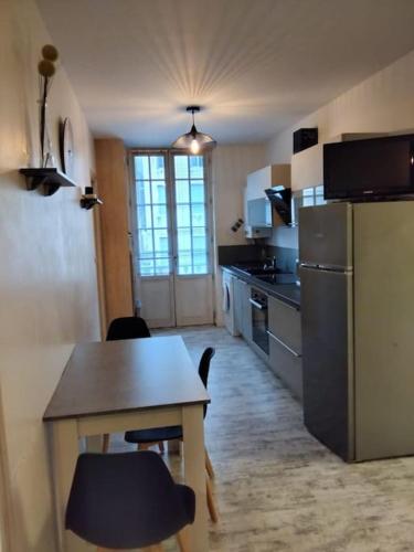 une petite cuisine avec une table et un réfrigérateur dans l'établissement Le thermal, à La Bourboule