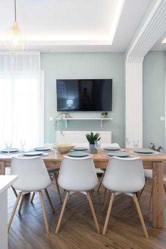 a dining room with a wooden table and white chairs at Homevision - Architectural Condo in Thessaloniki
