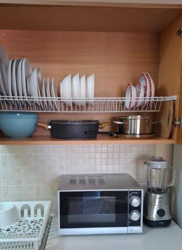 a kitchen with a microwave and plates on a shelf at By The Way Apartment 1 in Larnaka