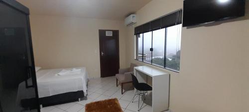a small room with a desk and a window at Âncora Hotel in Faxinal