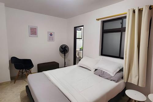 a bedroom with a white bed and a window at Duplex con terraza en el corazón de Envigado 300mb in Envigado