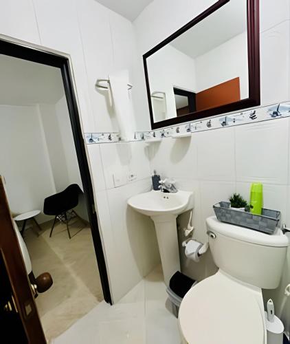 a bathroom with a toilet and a sink and a mirror at Duplex con terraza en el corazón de Envigado 300mb in Envigado