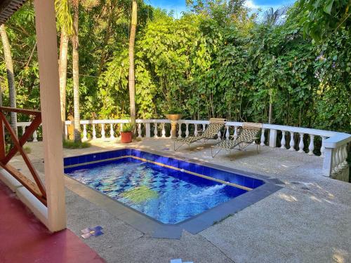 a swimming pool on a patio with two chairs at Hotel La Casablanca Tayrona in Calabazo