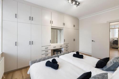 a white bedroom with two beds and a fireplace at Cozy and spacious full size flat in London