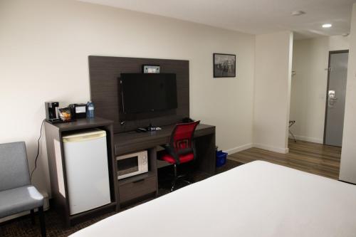 a bedroom with a desk with a tv and a bed at Ramada by Wyndham Dawson Creek in Dawson Creek