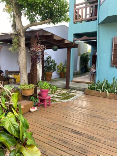 a wooden deck with plants and a blue building at Solar das Pétalas Guest House in Florianópolis