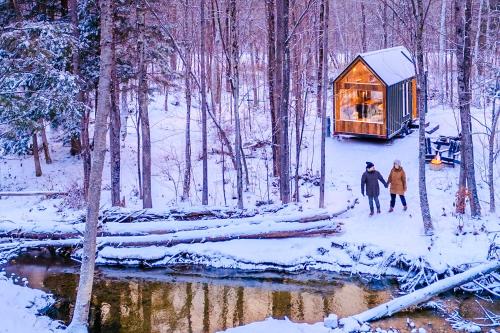 two people standing in the snow near a cabin in the woods at Lumen Nature Retreat in Woodstock