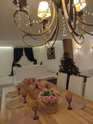a dining room table with flowers and a chandelier at Meteora Grande luxury suite & spa villa in Kalabaka