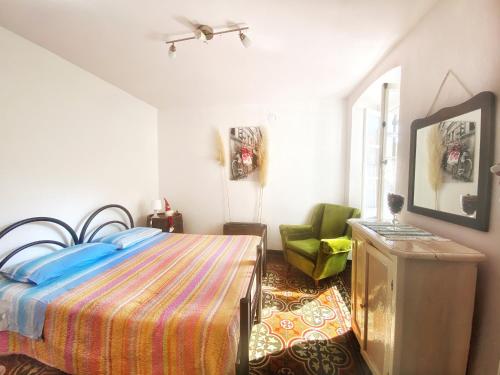 a bedroom with a bed and a green chair at La casa con giardino, vicino al ruscello segreto in Borzonasca