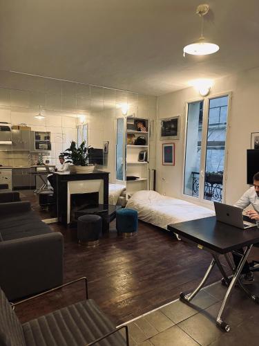 Cette chambre comprend un lit et un bureau avec un ordinateur portable. dans l'établissement Charmant Studio BASTILLE - Votre Havre de Paix au Cœur de Paris !, à Paris