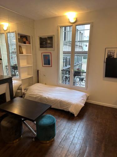 une chambre avec un lit, une table et une fenêtre dans l'établissement Charmant Studio BASTILLE - Votre Havre de Paix au Cœur de Paris !, à Paris